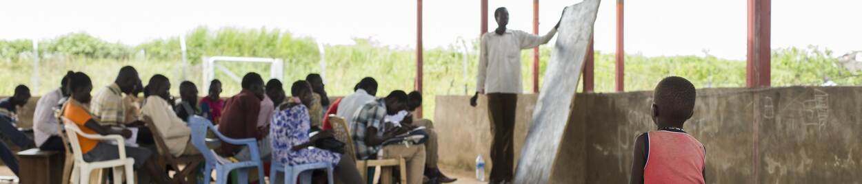 Kind kijkt toe bij volwassenenonderwijs in een klas in Juba, Zuid-soedan